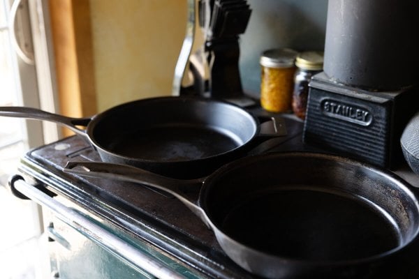 Two cast iron pans sitting on top of a wood cookstove.