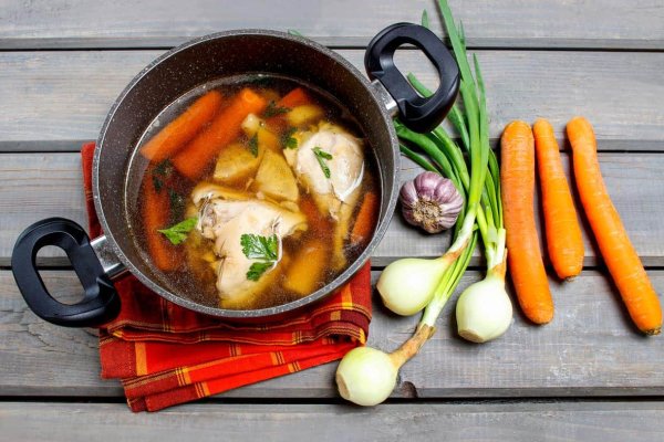 Chicken-Bone-broth-in-pot Chicken broth in a large pot with fresh veggies on the counter.