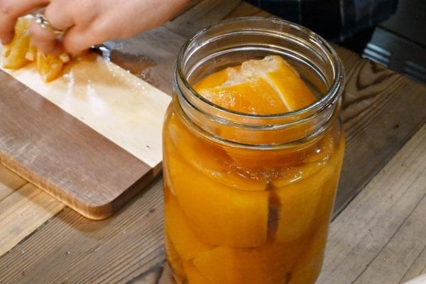 Preserved lemons in a jar with a cutting board and diced preserved lemons.