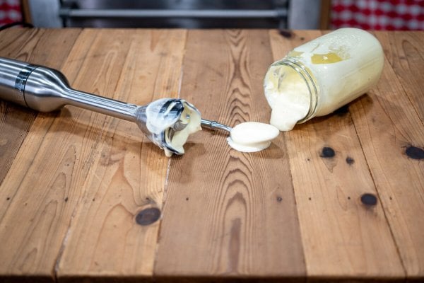 Mayonnaise in a jar next to an immersion blender.