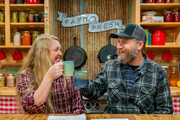A man and woman clicking their coffee cups together in cheers.