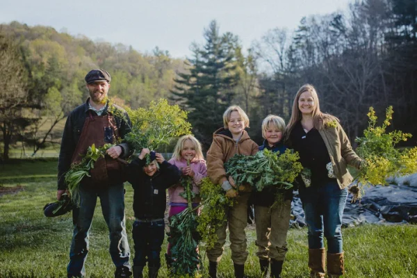 Rooted_May__Family_Web-12_720x A husband, wife and four children holding up garden produce.