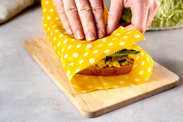 A sandwich being wrapped with yellow beeswax wrap.