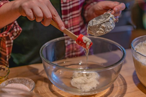 Sourdough starter being measured into a glass bowl.