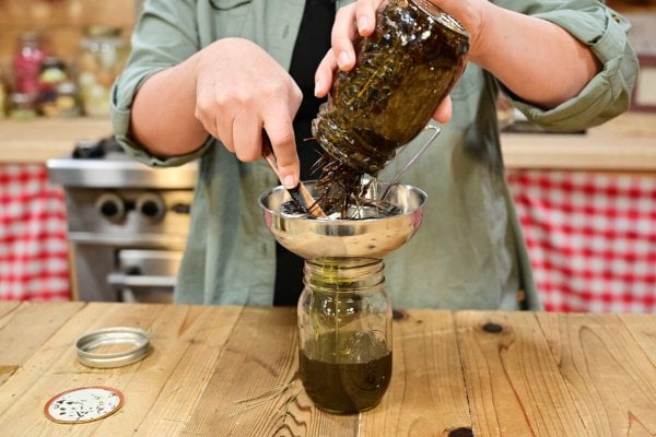 A woman straining a jar of herbal pine oil.