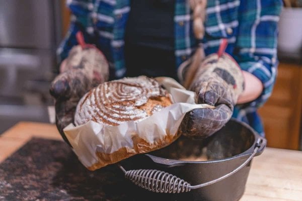 Fresh loaf of sourdough bread coming out of a cast iron dutch oven.